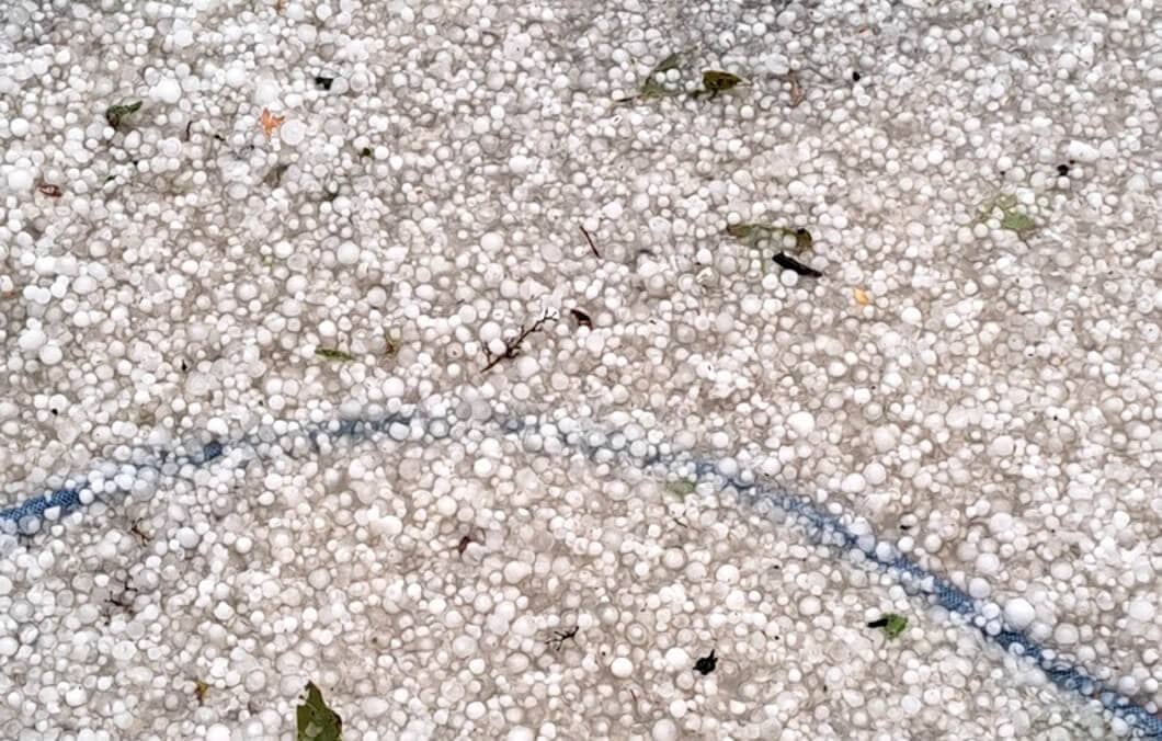 A garden hoe covered by hail stones