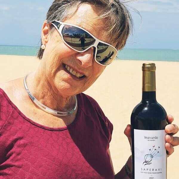 Irene with a bottle of Saperavi 2021 from Kvevri, Georgian natural wine, at a beach in Spain